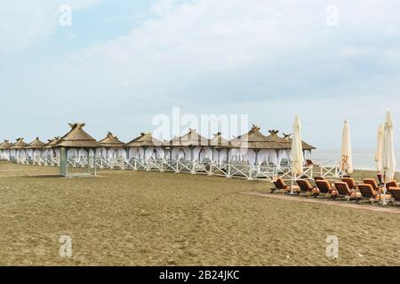 Ausgestattet mit Zelten mit Reetdach, am bewölkten Tag am einsamen Strand. Die Offseason Stockfoto