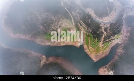 Antenne. Zauberhafter Blick vom Himmel durch Wolken und Nebel, den Stausee Odelouca Stockfoto