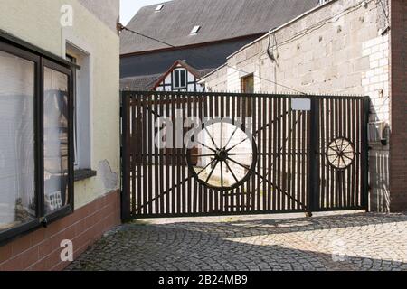 Holztor, antike Arbeit mit dekorativem Accessoire in Form eines Rundrads, im sonnigen Sommertag in der deutschen Stadt am Fluss Stockfoto
