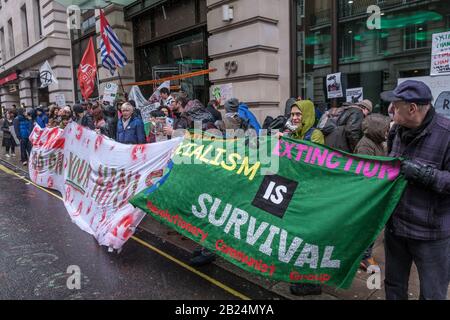 London, Großbritannien. Februar 2020. Die Menschen posieren mit den Bannern in einem Hagelsturm. Erdstreik und andere Klimaaktivisten protestieren in den Mayfair-Büros eines Teils des britischen multinationalen Bergbauunternehmens Glencore. Als einer der größten Kohlehersteller der Welt profitieren sie von der ökologischen Zerstörung, um Mineralien wie Kobalt, Kupfer und Lithium zu gewinnen, die in Smartphones, Computern und Elektroautos lebenswichtig sind. Kongolesische Familien verklagen sie wegen der in ihren Minen getöteten oder vermauerten Kinder, und Demonstranten gegen ihren Bergbau in mehreren Ländern wurden von der Polizei gewaltsam angegriffen oder ermordet. Peter Mar Stockfoto