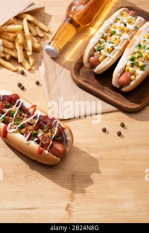 Köstliche Hot Dogs in der Nähe von Bier und Pommes frites auf Holztisch Stockfoto