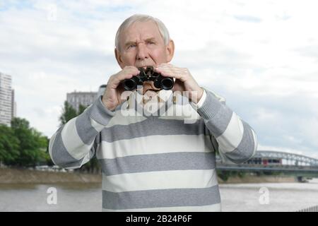 Ernsthafte alte ernsthafte Touristenbeobachtung im Fernglas. Stockfoto