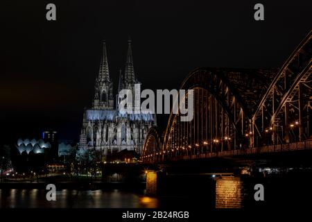 Der Kölner Dom und die Brücke von Hause aus sind die bekanntesten Wahrzeichen in Köln. Beide sind nachts beleuchtet. Stockfoto