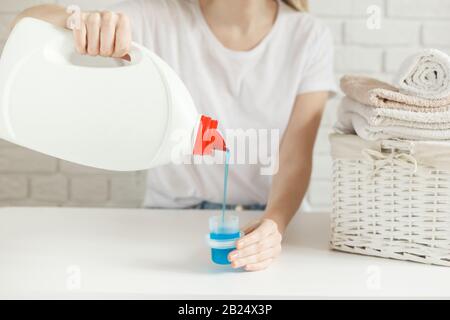 Frau gießt Waschmittel in die Kappe auf dem Tisch, Nahaufnahme. Wäschekonzept Stockfoto