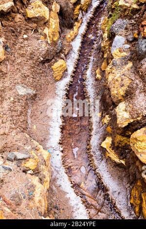 Ein Salzwasserstrom mit kristallisiertem Salz an den Seiten, Salzteiche von Maras (Salinas de Maras), Sacred Valley, Peru Stockfoto