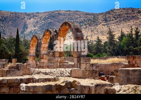 Ruinen von Bögen kleiner Paläste aus der Umayyaden-Ära in Anjar, Bekaa-Tal, Libanon, Naher Osten. Das Anti-Libanon-Gebirge ist im Hintergrund. Stockfoto