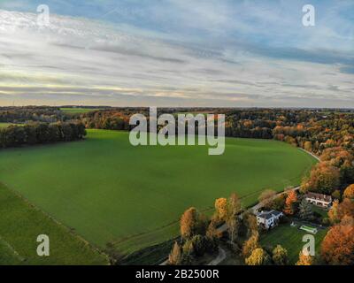 Blick auf die Landseite in Wallonien, Belgien, Luxusvillen und Bauernhaus, umgeben von Wald und Ackerland bei schönem Sonnenuntergang. Stockfoto