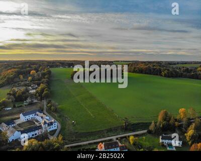 Blick auf die Landseite in Wallonien, Belgien, Luxusvillen und Bauernhaus, umgeben von Wald und Ackerland bei schönem Sonnenuntergang. Stockfoto