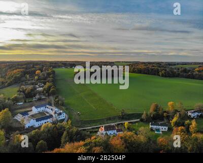 Blick auf die Landseite in Wallonien, Belgien, Luxusvillen und Bauernhaus, umgeben von Wald und Ackerland bei schönem Sonnenuntergang. Stockfoto