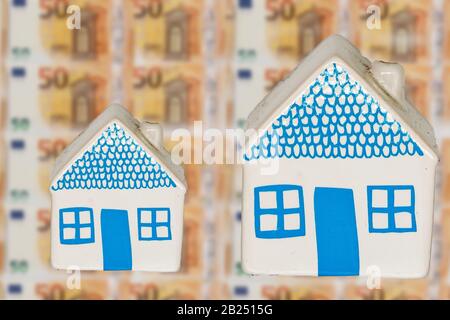 Zwei unterschiedlich breite Häuser auf einem Hintergrund von 50 Euro-Banknoten Stockfoto