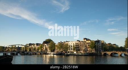 Amsterdam, NIEDERLANDE - 10. JANUAR 2017: Berühmte alte Gebäude und Kanäle der Stadt Amsterdam bei Sonnenuntergang. Allgemeine Querformatansicht. Stockfoto