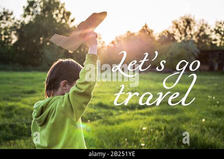 Kind startet Papierflieger. Junge, grüne Jacke über Feld bei Sonnenuntergang läuft. Glückliche Kindheit. Zu Fuß auf der Straße ohne ein Telefon. Stockfoto