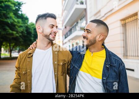 Porträt eines glücklichen schwulen Paares, das Zeit zusammen verbringt, während er auf der Straße spazieren geht. LGBT und Love Konzept. Stockfoto