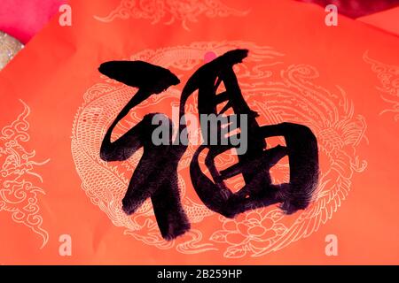 Der Chinesische Handschriftensegen "Fu" wurde auf dem roten Papier mit chinesischem Drachenmuster isoliert. Das chinesische "Fu", das auf rotem Hintergrund schreibt, lu Stockfoto