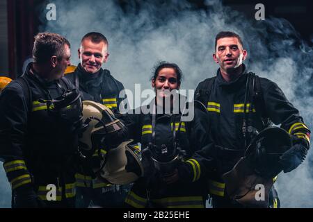 Gruppenbild der Feuerwehrleute mit Rauch des Feuerlöschers im Hintergrund Stockfoto