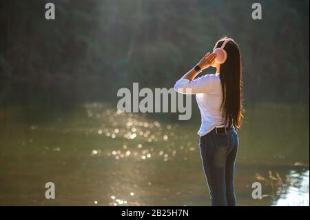 Junge Leute hören gerne Musik in ihren Kopfhörern inmitten der Natur und dem warmen Licht des Morgens. Stockfoto