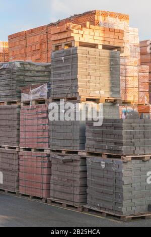 Mehrere Paletten mit Beton Ziegel übereinander im Depot gestapelt. Die industrielle Produktion von Backsteinen. vertikale Foto. Stockfoto