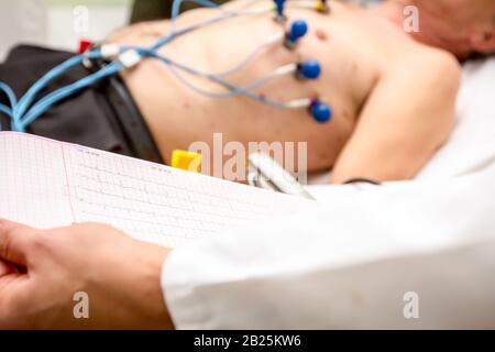 Der kardiologe Holding und Überprüfung des Elektrokardiographen EKG oder EKG-Diagramm auf Raster Papier gedruckt. Stockfoto