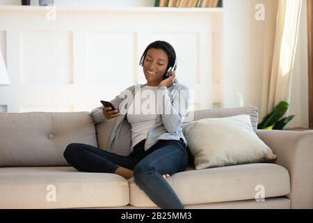 Afroamerikanische Frau im Kopfhörer mit Smartphone-Gadget Stockfoto