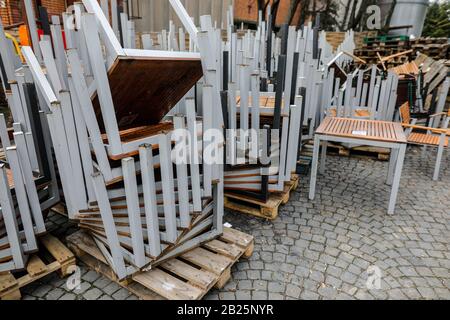 Haufen alter Tische aus Eisen und Holz, die an einem bewölkten Wintertag außerhalb des Restaurants gestapelt sind. Stockfoto