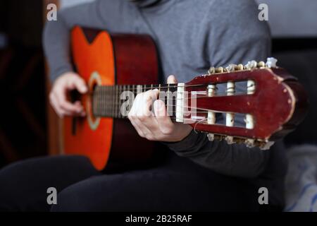 Mädchen, das eine sechssaitige Akustikgitarre mit Nylonsaiten spielt. Stockfoto
