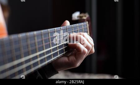 Weibliche Hand hält einen Akkord auf einer akustischen Gitarre Stockfoto