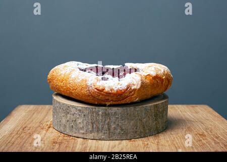 Blätterteig mit Kerrys und Pudding auf einem Holzwaldständer auf grauem Hintergrund dicht mit Puderzucker bestreut. Stockfoto