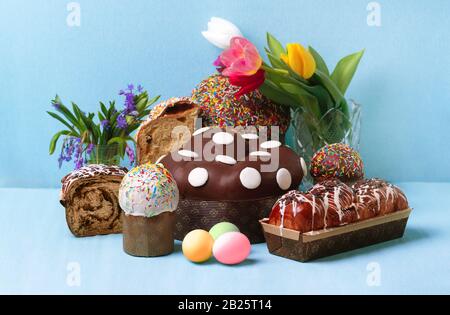 Osterkuchen und Frühlingsblumen, osterbrot und Eier über blauem Hintergrund Stockfoto