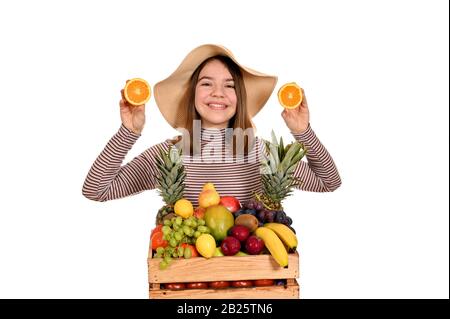 Glückliches Mädchen mit Obst in der Holzkiste und Orangen Stockfoto