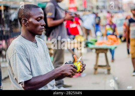 Ein Orangenverkäufer schält Orangen zum Verkauf auf einer Straße in Lagos, Nigeria. Stockfoto