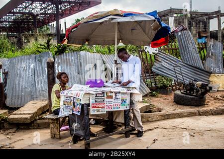 Die Leute hören auf, Zeitungen auf einem Zeitungsstand auf einer Straße in Lagos, Nigeria zu lesen. Stockfoto