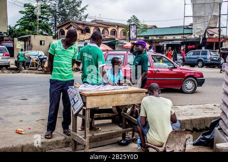 Die Leute hören auf, Zeitungen auf einem Zeitungsstand auf einer Straße in Lagos, Nigeria zu lesen. Stockfoto