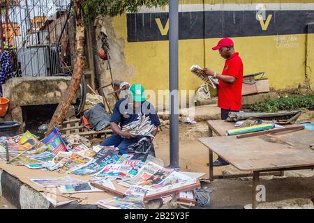 Die Leute hören auf, Zeitungen auf einem Zeitungsstand auf einer Straße in Lagos, Nigeria zu lesen. Stockfoto