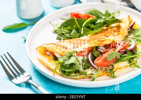 Omelette mit grünen Blättern an der weißen Platte. Stockfoto