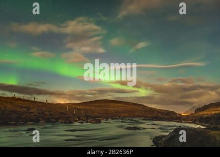 Aurora in Island Nordlicht helle Balken, die in grünen Balken aufsteigen, die im Fluss reflektieren Stockfoto