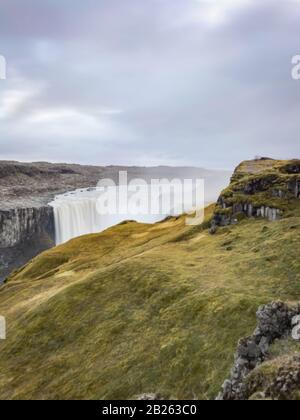 Dettifoss Wasserfall in Island lange Wasserbelastung, die über den Rand hinter einer dicken Grasschicht fällt Stockfoto