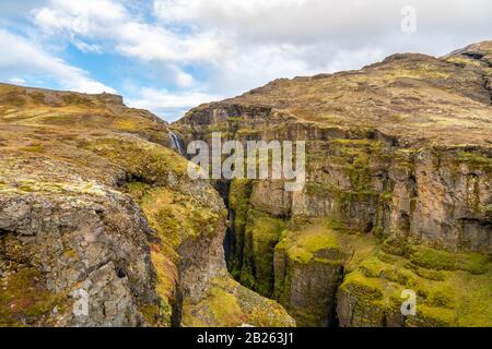 Glymur-Wasserfall in der Icelandacht hinter überwucherten grünen Klippen Stockfoto