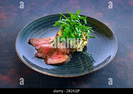 Scheiben gegrilltes Rindfleisch mit Kartoffel, eingelegten Gurken und Oliven Stockfoto