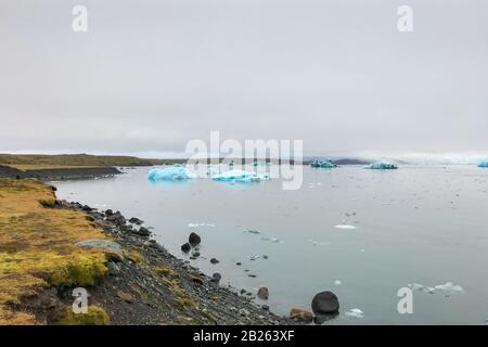 Joekulsarlon Glacier Lagoon tiefblauer Eisberg, der in Richtung atlantischer Küstenlinie driftet Stockfoto