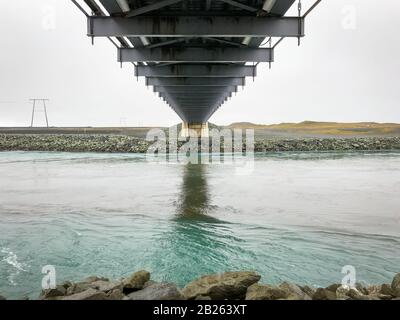 Die Joekulsarlon Glacier Lagoon führt zum atlantik, der unter der Hängebrücke steht Stockfoto