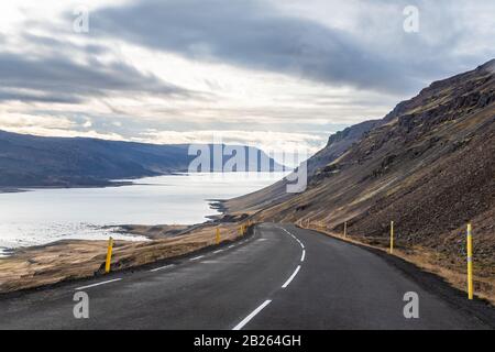 Fahrt auf der Straße in Island steiler Abstieg in den Fjord zwischen schwarzen Bergen Stockfoto