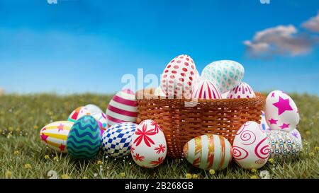 Bunte ostereier in braunem Korb auf grünem Gras mit blauem Himmel. 3D-Abbildung. Stockfoto