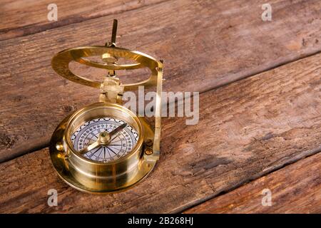 Antiker goldener Kompass, der auf einer alten Holztafel liegt Stockfoto