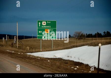 Grünes Straßenschild, das die Richtung zu verschiedenen Zielen angibt, im Hintergrund blauer Himmel ohne Wolken. Stockfoto