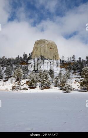 Devils Tower National Monument, Blauer Himmel mit weißen Wolken, verschneite Wiese. Stockfoto