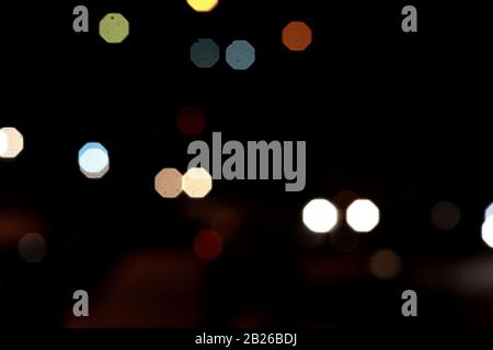 Helle Flecken, die in der Nacht mehrfarbig auf dunklem Hintergrund leuchten, leuchten. Garland. Stockfoto