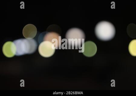 Helle Flecken, die in der Nacht mehrfarbig auf dunklem Hintergrund leuchten, leuchten. Garland. Stockfoto