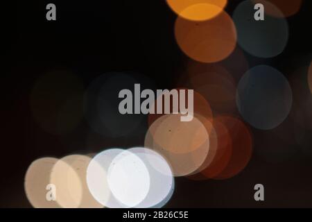 Helle Flecken, die in der Nacht mehrfarbig auf dunklem Hintergrund leuchten, leuchten. Garland. Stockfoto