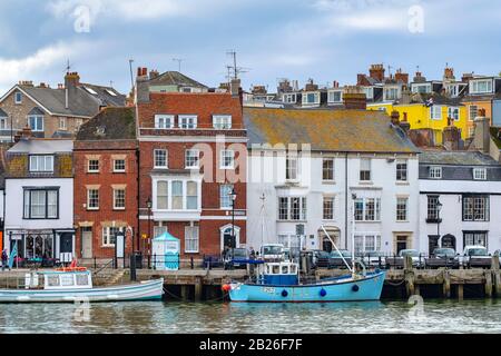 Segelyachten und Boote im Weymouth Harbour mit bunten Häusern an der Jura-Küste von Dorset, South West, Großbritannien Stockfoto