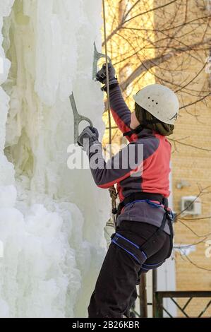 Mädchen klettert auf Eis Kletterwettbewerb nach oben Stockfoto